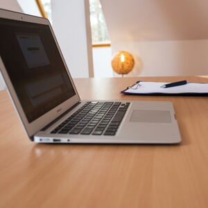 aufgeklappter Laptop und Klemmbrett mit Stift