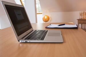 aufgeklappter Laptop und Klemmbrett mit Stift